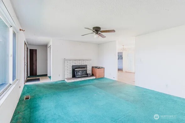 unfurnished living room with a healthy amount of sunlight, carpet flooring, visible vents, and a ceiling fan