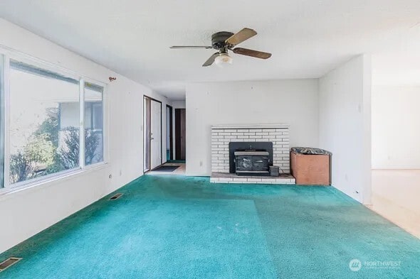 unfurnished living room featuring carpet, visible vents, and a ceiling fan