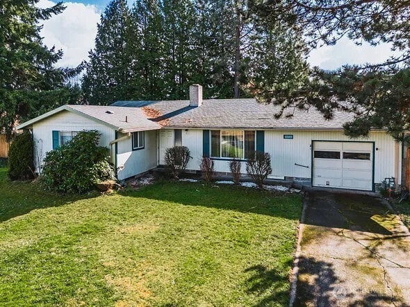 ranch-style home with a garage, driveway, a chimney, and a front yard