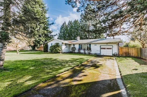 ranch-style home with a garage, fence, concrete driveway, and a front yard