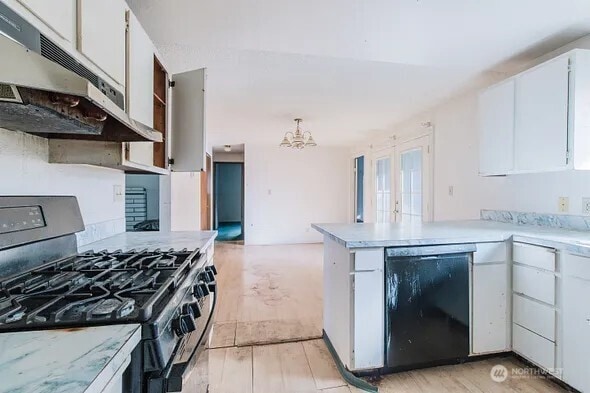 kitchen featuring light wood-style flooring, under cabinet range hood, a peninsula, white cabinets, and black appliances