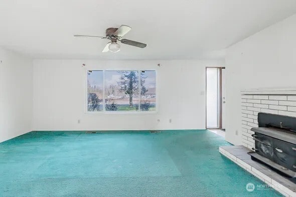 unfurnished living room with carpet and a ceiling fan