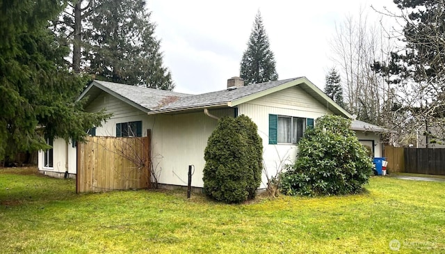 view of property exterior with a lawn, a chimney, roof with shingles, an attached garage, and fence