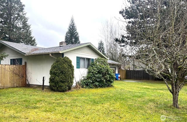 view of side of property with an attached garage, central AC, fence, a yard, and a chimney