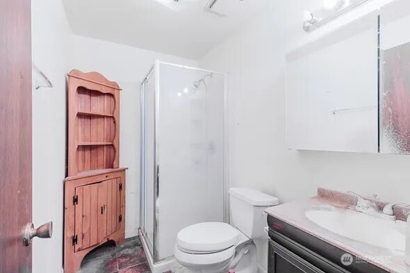 bathroom featuring toilet, a stall shower, and vanity