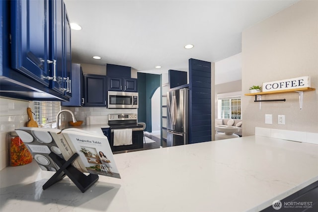 9100 Lewis Dr NE, Lacey, WA 98516 - kitchen with stainless steel appliances, blue cabinetry, recessed lighting, decorative backsplash, and a peninsula