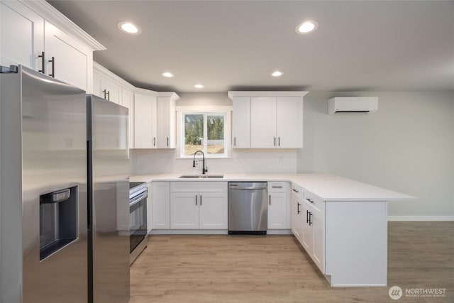 6490 Watson Loop, Maple Falls, WA 98266 - kitchen featuring stainless steel appliances, a peninsula, a sink, light wood-type flooring, and a wall mounted AC