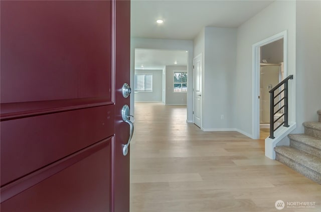 hall featuring light wood-style flooring, stairway, and baseboards