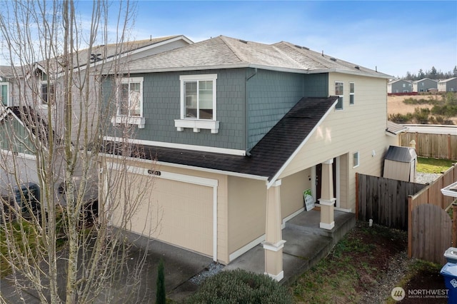 view of front of house with roof with shingles, fence, driveway, and an attached garage