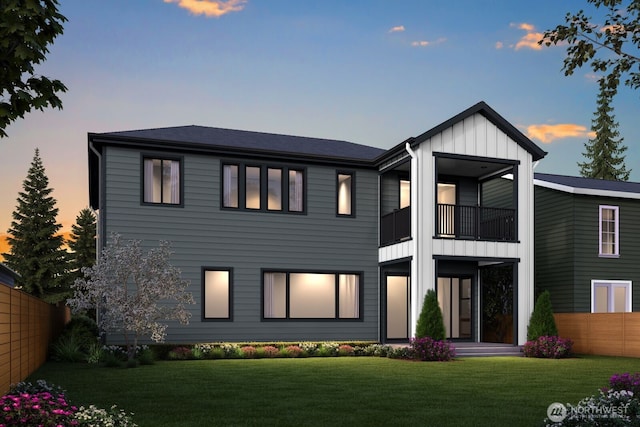 rear view of property featuring a balcony, fence, board and batten siding, and a yard