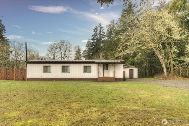 manufactured / mobile home with a storage unit, fence, an outbuilding, and a front yard