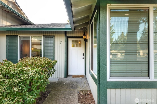 view of exterior entry with a shingled roof