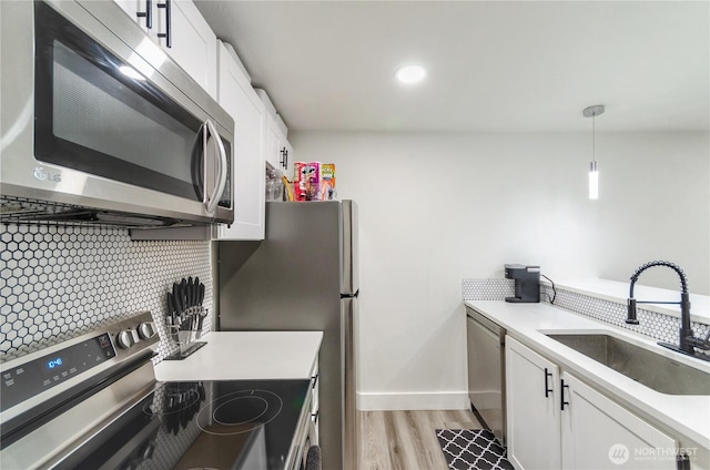 kitchen with stainless steel appliances, white cabinetry, a sink, and tasteful backsplash