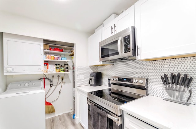 kitchen with stainless steel appliances, backsplash, stacked washer and clothes dryer, and white cabinetry