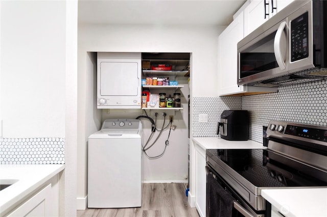 laundry room with laundry area, stacked washer and clothes dryer, and light wood-style flooring