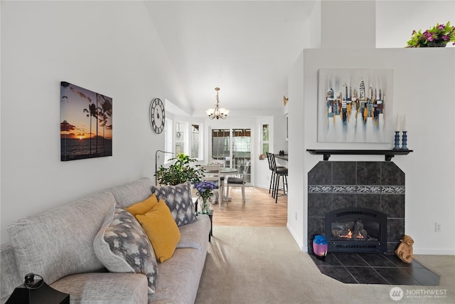 carpeted living room with a chandelier, a fireplace, high vaulted ceiling, and baseboards