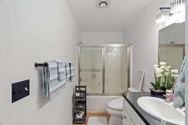 full bathroom with combined bath / shower with glass door, vanity, toilet, and wood finished floors