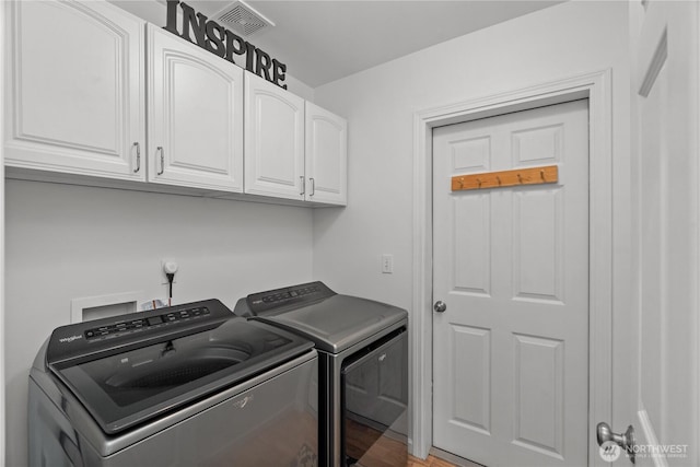 laundry room with visible vents, washing machine and dryer, and cabinet space