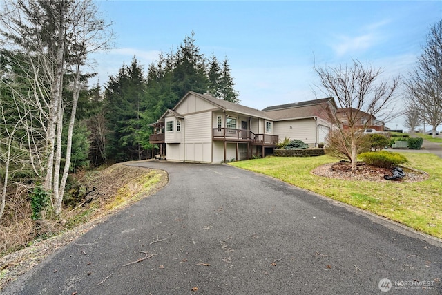 view of front of home with aphalt driveway, board and batten siding, and a front lawn