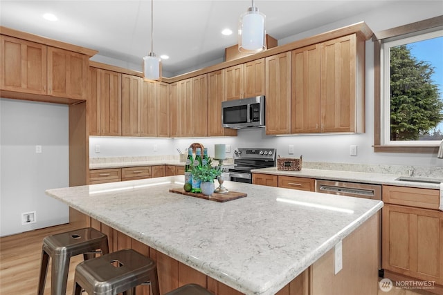 kitchen with a breakfast bar, a center island, recessed lighting, appliances with stainless steel finishes, and a sink