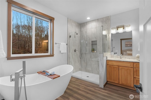 full bathroom featuring recessed lighting, wood finished floors, vanity, a soaking tub, and a stall shower