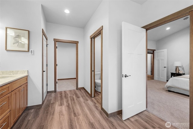 hall featuring light wood-style floors, recessed lighting, and baseboards