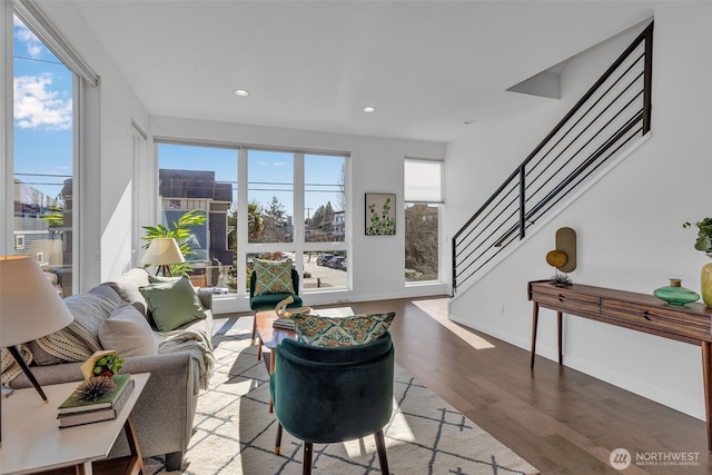 living area with stairway, wood finished floors, a wealth of natural light, and recessed lighting