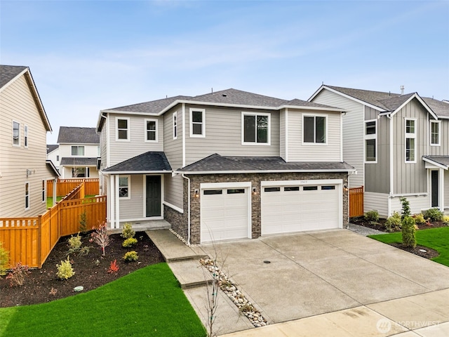 view of front of property featuring an attached garage, stone siding, fence, and concrete driveway