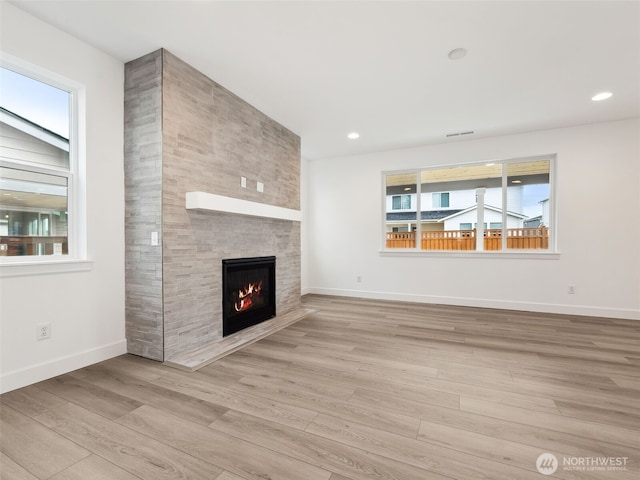 unfurnished living room with light wood finished floors, a large fireplace, visible vents, baseboards, and recessed lighting