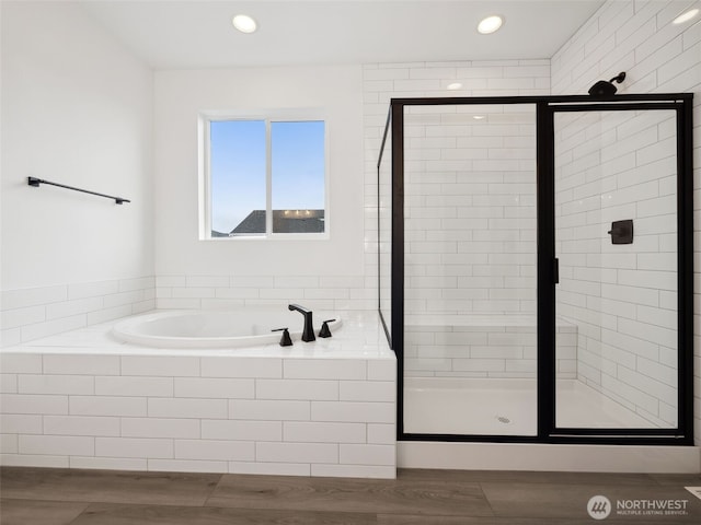 bathroom featuring a stall shower, a garden tub, recessed lighting, and wood finished floors