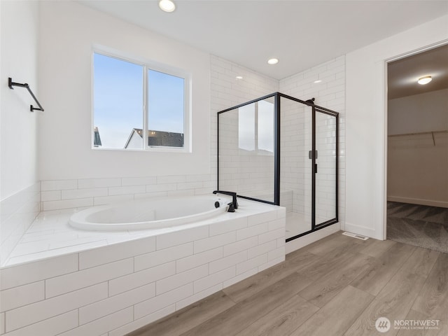 bathroom featuring a stall shower, a spacious closet, wood finished floors, and recessed lighting