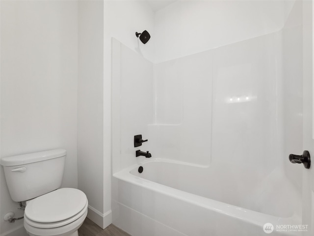 full bath featuring shower / washtub combination, toilet, and wood finished floors