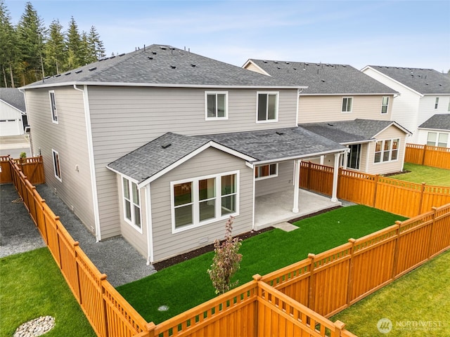 rear view of property with a shingled roof, a fenced backyard, and a lawn