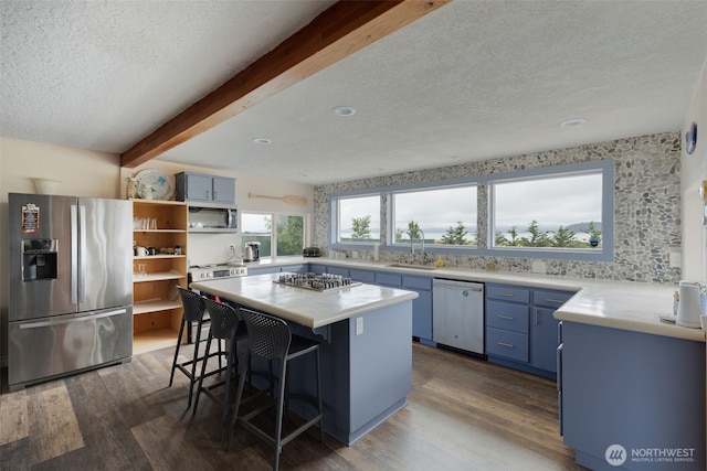kitchen with open shelves, beam ceiling, appliances with stainless steel finishes, blue cabinets, and dark wood-style flooring