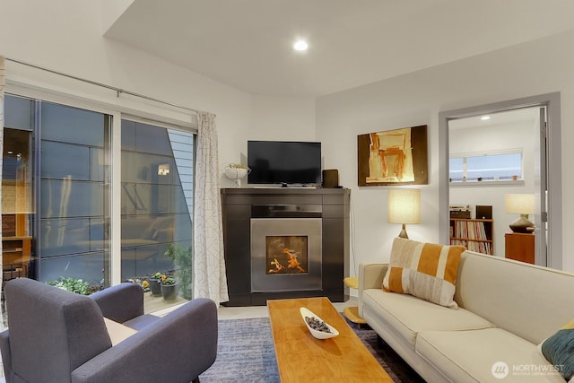 living area featuring recessed lighting and a glass covered fireplace