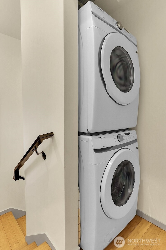 washroom featuring stacked washing maching and dryer, baseboards, laundry area, and light wood-style floors