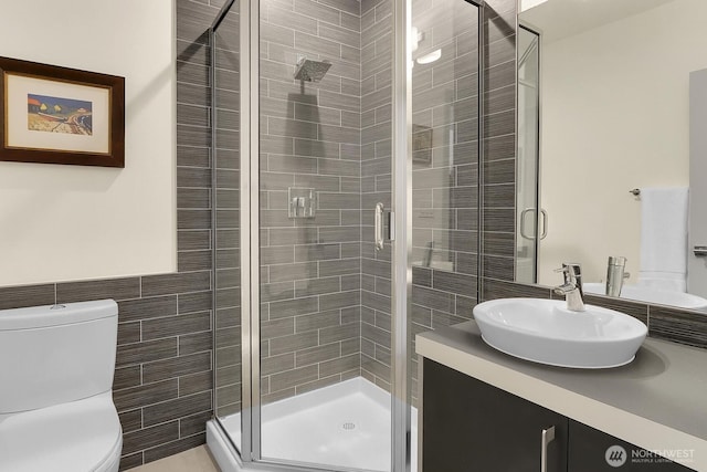 bathroom featuring a shower stall, toilet, and vanity