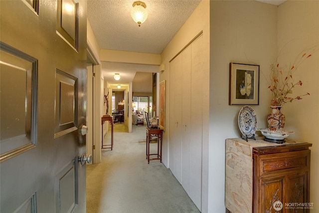 hallway with light carpet and a textured ceiling