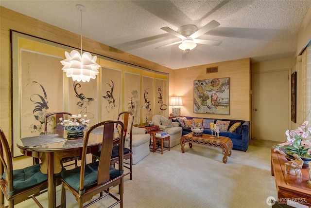 dining space featuring carpet floors, ceiling fan, visible vents, and a textured ceiling