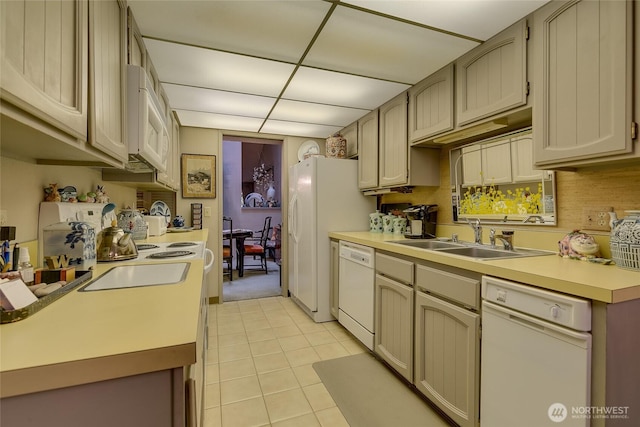 kitchen with light countertops, white appliances, light tile patterned flooring, and a sink