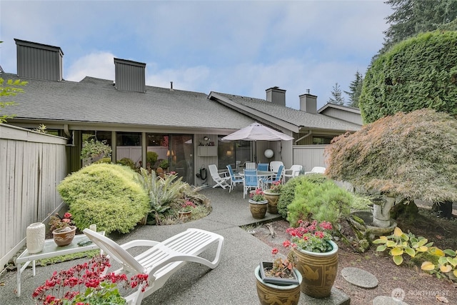 rear view of house with a patio, outdoor dining area, roof with shingles, and fence