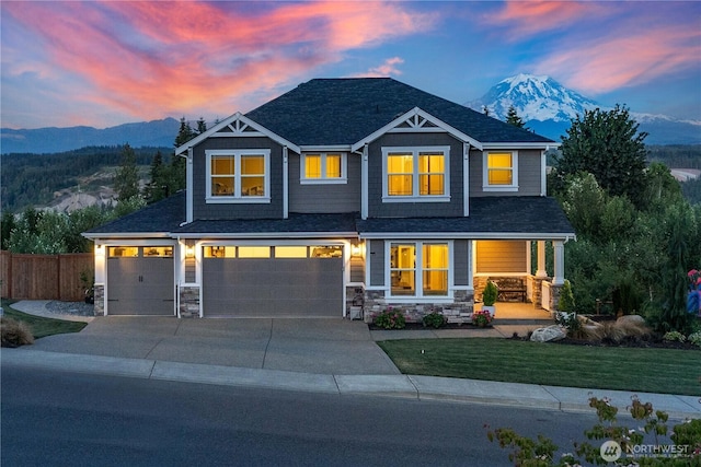 craftsman-style house with stone siding, fence, a yard, a mountain view, and a porch