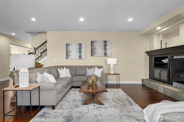 living area with recessed lighting, dark wood-style flooring, baseboards, and stairs