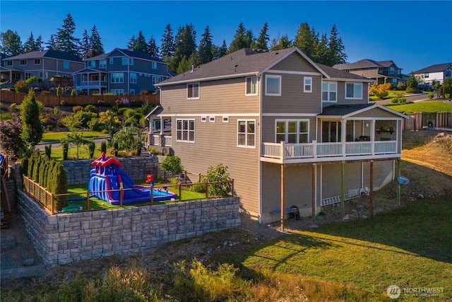 rear view of house with a residential view, a lawn, and fence