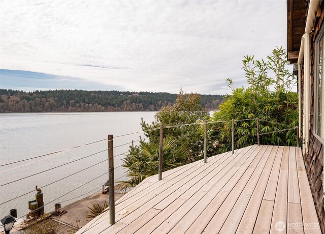 wooden deck with a water view and a forest view