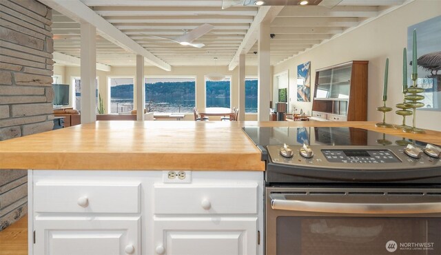 kitchen featuring butcher block counters, white cabinetry, beam ceiling, and stainless steel electric stove