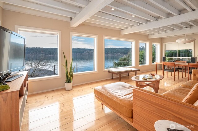 sunroom featuring beamed ceiling and a water view