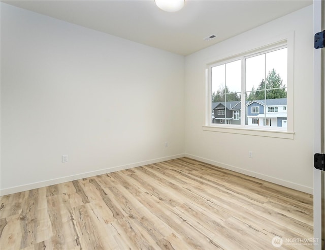 spare room featuring light wood-style floors, visible vents, and baseboards