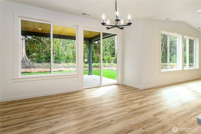 interior space featuring light wood-style floors, plenty of natural light, baseboards, and an inviting chandelier