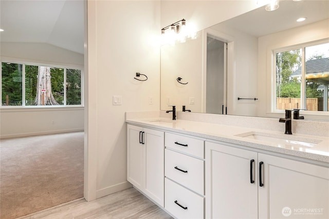 full bath with vaulted ceiling, double vanity, a sink, and baseboards